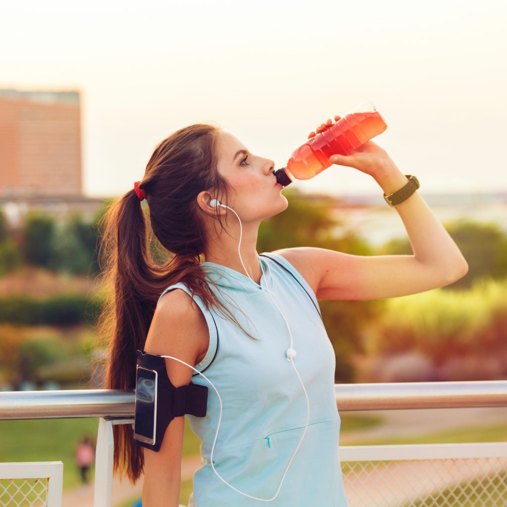 a woman drinks a beverage while doing sports