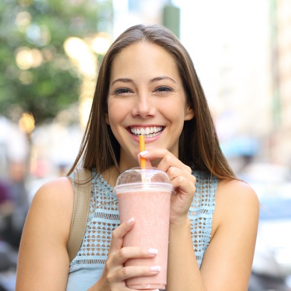 Uśmiechnięta kobieta pijąca słodki koktajl z cukrem.