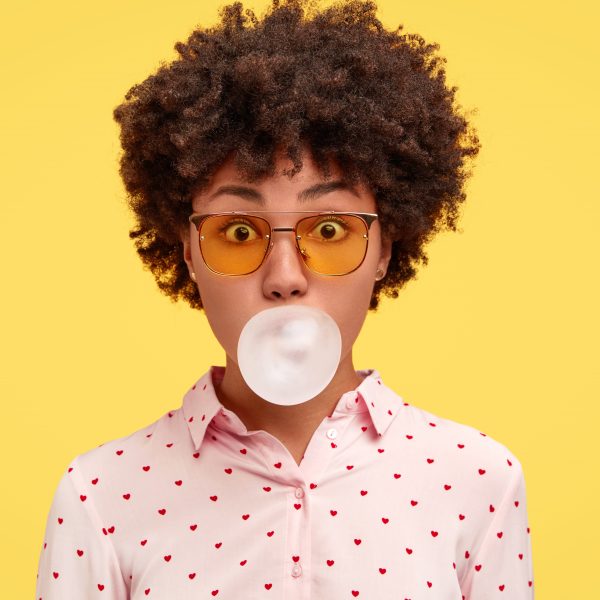 Jeune femme faisant une bulle avec un chewing-gum